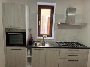 Een koelkast, een oven, kookgerei, borden en bestek