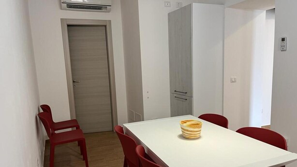 A small, modern room with a white table and red chairs, a wardrobe, and a door. - A1 SOLE - APARTMENT WITH 6 BEDS (Balestrate)