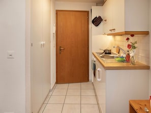 Cocina compacta con puerta de madera, un lavamanos, estufa y una pequeña encimera con un florero.