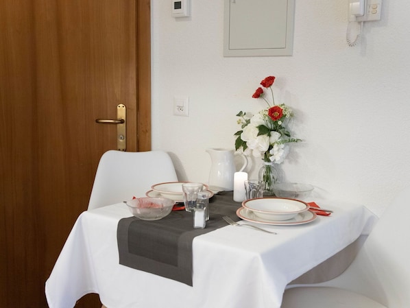 Et spisebord dækket med tallerkener, glas, en kande og en vase med blomster.