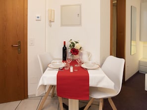 A dining table set with plates, glasses, a wine bottle, and a vase with flowers.