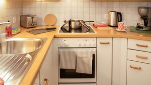 Une cuisine moderne avec des meubles blancs, un évier en acier inoxydable, un grille-pain, une bouilloire et une machine à café.