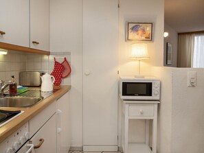 A compact kitchen with a microwave, kettle, and a small cabinet. - Beautiful apartment for 2 guests with WIFI, TV, balcony and pets allowed (Grindelwald)