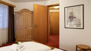 A hotel room with two beds, a wardrobe, a framed picture, and a small stool.
