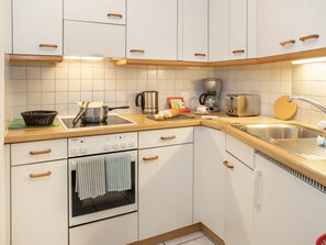 Uma cozinha com armários brancos, um forno Siemens, uma cafeteira e uma torradeira.