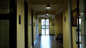 A hallway with a wooden floor, framed pictures on the walls, and pendant lighting. - The Royal Kargil (Kargil)