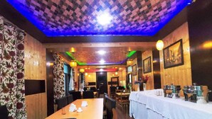 A restaurant with a long wooden table, chairs, and a buffet setup. - The Royal Kargil (Kargil)