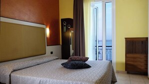 A hotel room with a bed, a nightstand, a lamp, and a view of the sea through the window. - The Royal Kargil (Kargil)