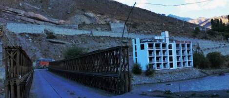 Eine Brücke mit Metallgeländer und ein Gebäude mit weißer Fassade und zahlreichen Fenstern.