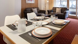 Un coin repas avec une table dressée pour quatre personnes, un canapé et une fenêtre donnant sur un beau paysage.