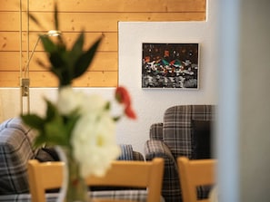 Een kamer met houten paneelwanden, een lijst met abstract schilderij en meubels met een geruite stof.