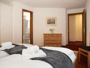 Habitación de hotel con cama, cómoda de madera, espejo y un cuadro en la pared.