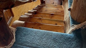 A wooden staircase leading to a log cabin interior with a sofa and a deer head mounted on the wall. - Full Log Family Lodge - private dock/beach & fire pit (Hackensack)