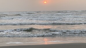 Une plage avec des vagues et un coucher de soleil.