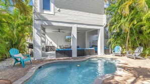 A pool area with a covered seating area, lounge chairs, and a ceiling fan. - La Coconut: 1 Block to Beach! Dog Friendly! Ping Pong & Foosball, Heated Pool by Anna Maria Life (Holmes Beach)