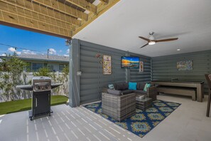 Enjoy al fresco dining and relaxation in this outdoor space with a barbecue grill, comfortable seating area, and flat-screen TV.