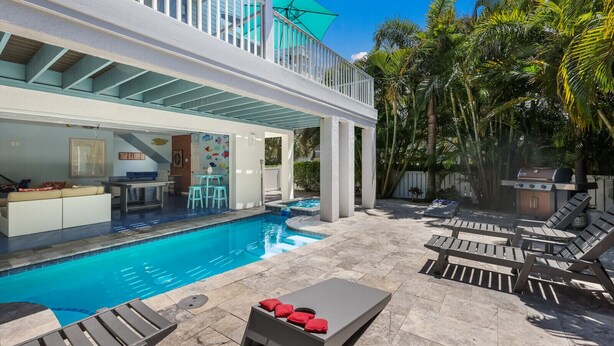 A pool area with lounge chairs, a table, and a bar area with a grill. - Meant to Be:1 Block to Beach! North End! Pool & Spa,Loaded Game Room by Anna Maria Life (Anna Maria)