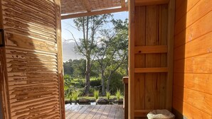 Une cabane en bois offrant une vue sur un jardin luxuriant et dotée d’une terrasse en bois.