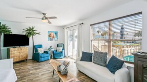 A living room with a white sofa, blue armchairs, a wooden coffee table, and a TV.