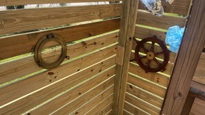 A wooden cabin with horizontal slats, a circular window, and a wooden wheel.