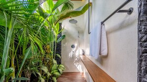 A wooden staircase leading to a shower area with a stone wall and lush green plants. - Green Flow Villa 17 (Ubud)