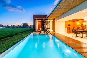 A modern house with a swimming pool, wooden deck, and a dining area with outdoor furniture.
