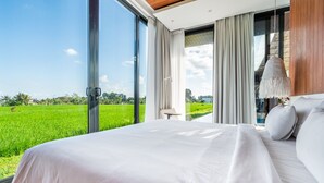 A bedroom with a large bed, a view of a green field, and a modern interior design. - Green Flow Villa 17 (Ubud)
