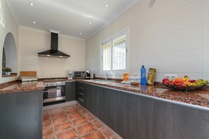 A modern kitchen with a built-in oven, microwave, and stove, a large window, and a fruit bowl on the counter.