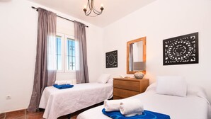 A hotel room with two beds, a wooden dresser, a mirror, and artwork on the walls.