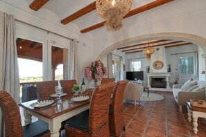 A dining area with wicker chairs, a table set for two, and a view of the outdoors.