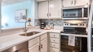 A modern kitchen with white cabinets, stainless steel appliances, and a tiled backsplash.