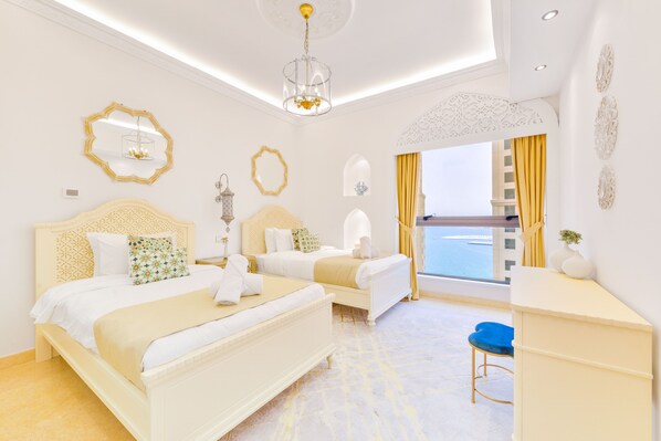 A hotel room with two beds, a desk, a chair, and a large window with a view.