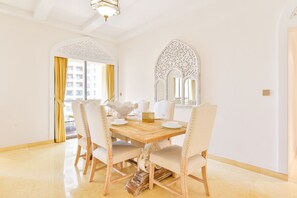A dining area with a wooden table, white upholstered chairs, and ornate wall mirrors.