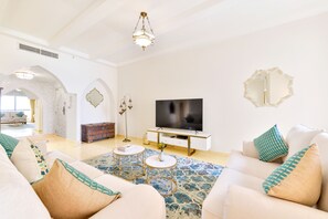 Relax in this stylish living room with a large flat-screen TV, beige sofa, and patterned rug.