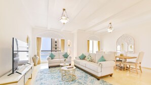 A spacious living room with a large sofa set, a coffee table, and a dining area with a table and chairs.
