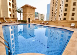 Relax by the rectangular pool surrounded by lounge chairs and a poolside bar.