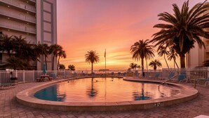 A swimming pool with a sunset view, surrounded by palm trees and lounge chairs. - Jamaica Royale Villa: Modern 1BR Retreat – Sleeps 6 with Private Beach Access and VIP Perks Daily! (Sarasota)