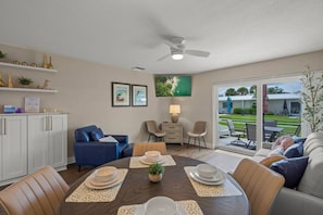 A dining area with a round table, chairs, and a ceiling fan. - Modern 1BR Villa | Private Beach | Sleeps 6 | Pool (Sarasota)