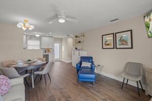 A spacious living area with a dining table, two chairs, a blue armchair, and a grey armchair. - Modern 1BR Villa | Private Beach | Sleeps 6 | Pool (Sarasota)