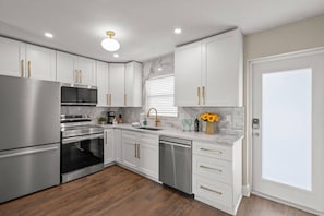 A modern kitchen with stainless steel appliances, white cabinetry, and a marble backsplash. - Modern 1BR Villa | Private Beach | Sleeps 6 | Pool (Sarasota)