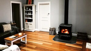 Een woonkamer met een open haard, een bank, een salontafel en een boekenkast.