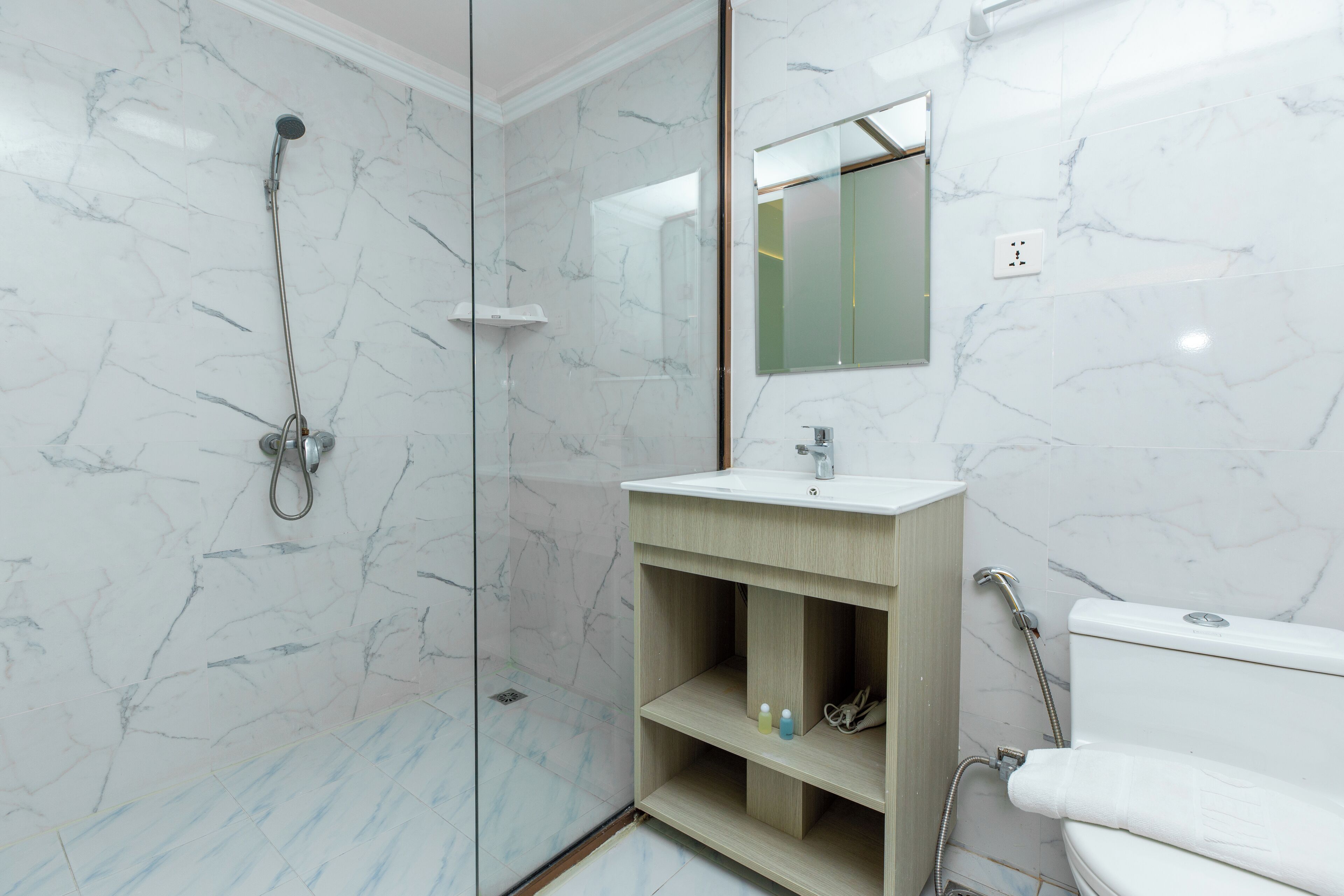 A modern bathroom with a glass-enclosed shower, a wooden vanity, and a white toilet.