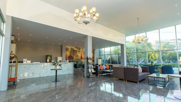 A spacious lobby with a marble reception desk, comfortable seating area, and large windows offering a view of the outdoors. - lucky Elephant Hotel (Bangkok)