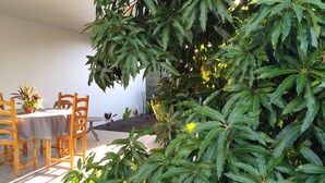Un espace de restauration en plein air, avec une table et des chaises, entouré d’une végétation luxuriante et offrant une vue sur le paysage extérieur.