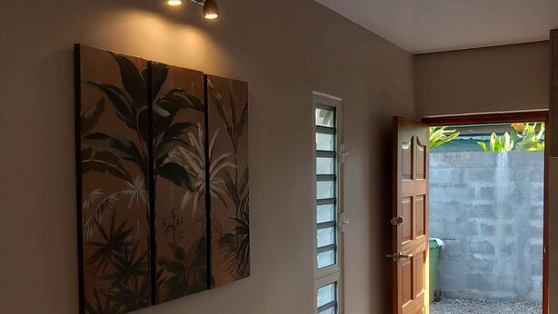 Un couloir avec un grand tableau, une porte donnant sur l’extérieur et une petite table.