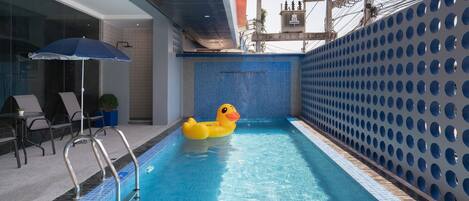 A swimming pool with a yellow inflatable duck, metal pool ladder, and blue tiled walls.
