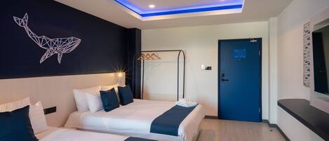 A modern hotel room with two beds, a geometric wall art, a blue door, and a mounted TV.