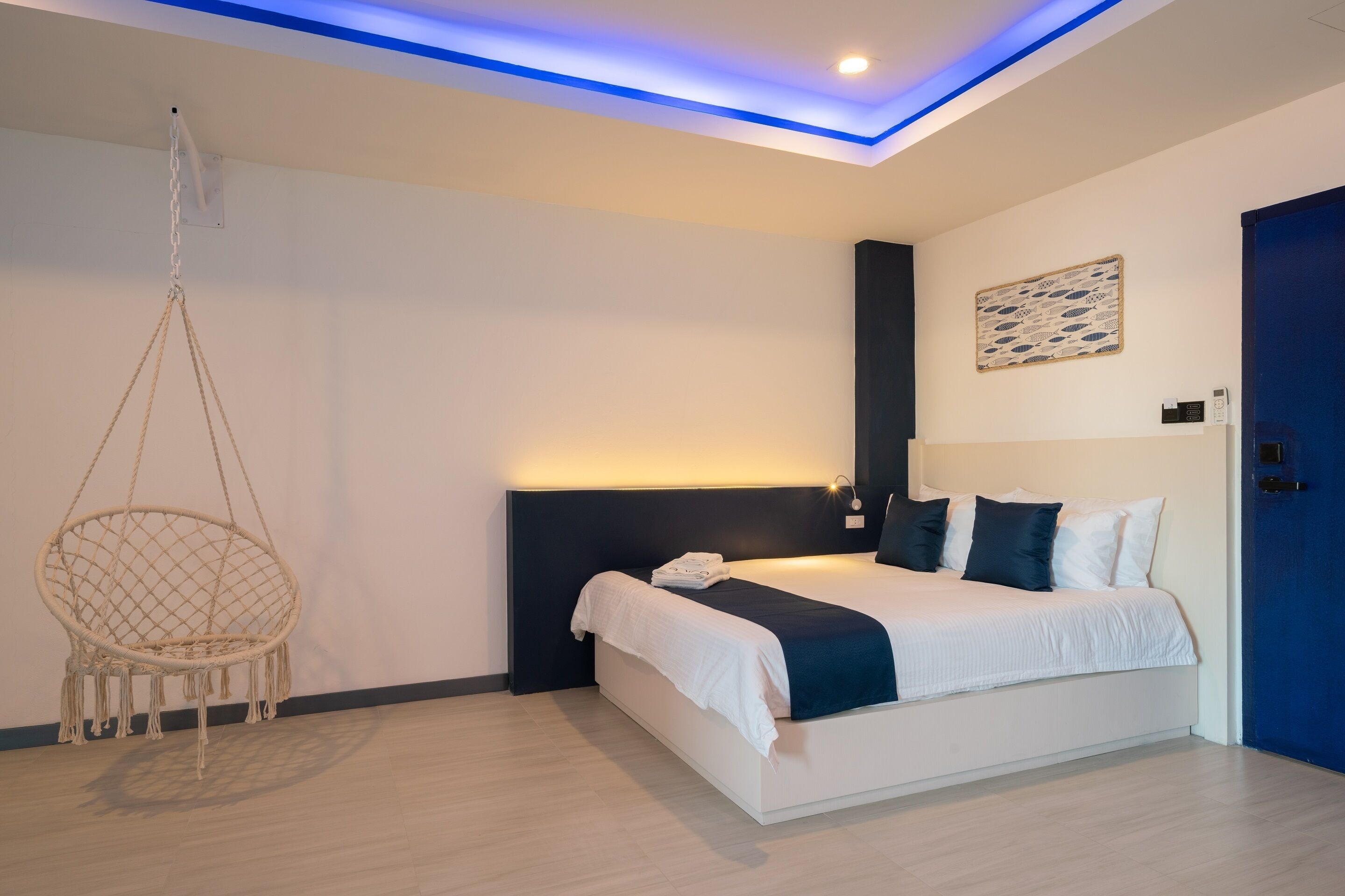 Un dormitorio moderno con una cama, una silla colgante y una puerta azul.
