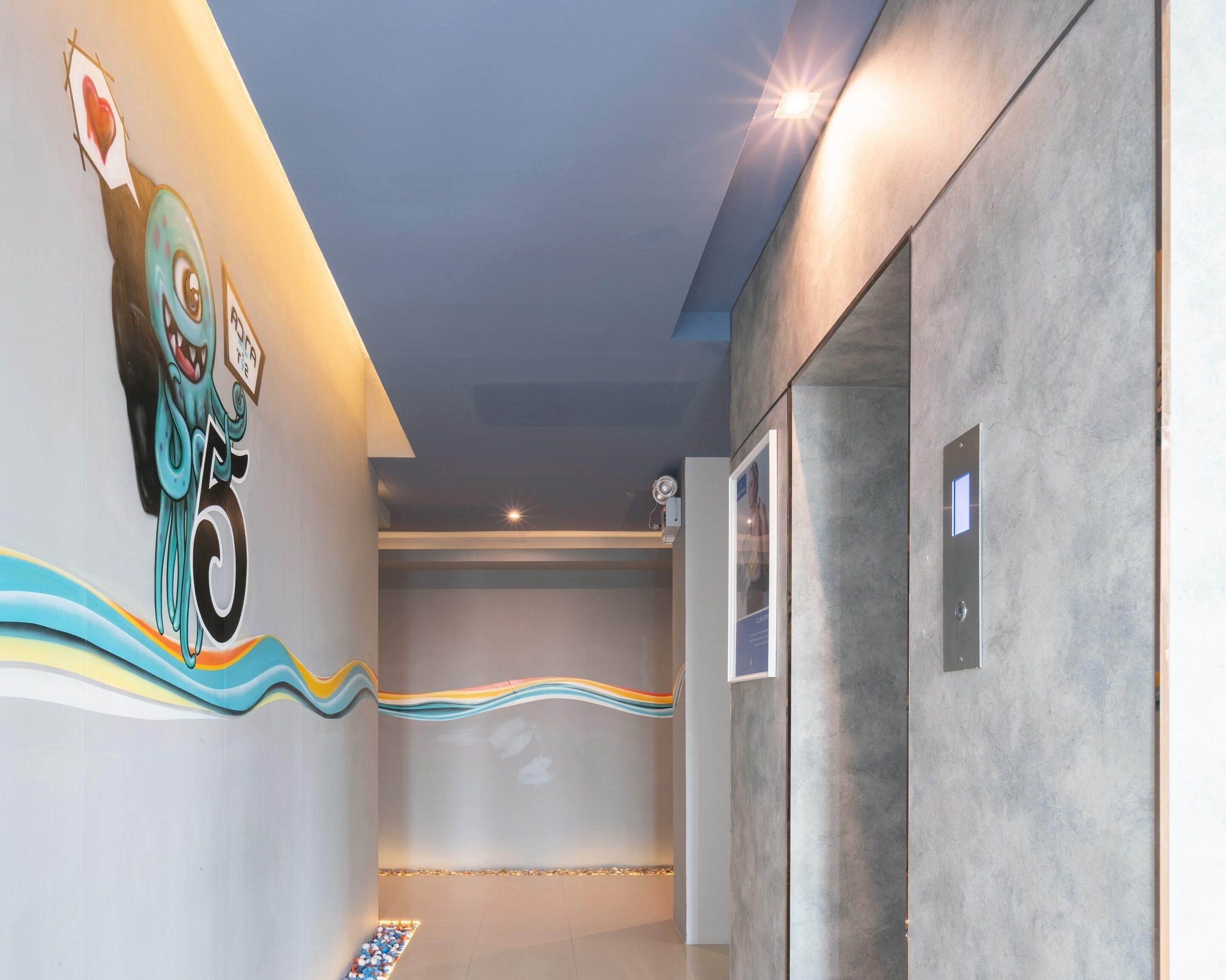 A modern hallway with a colorful mural, a light fixture, and a textured wall.