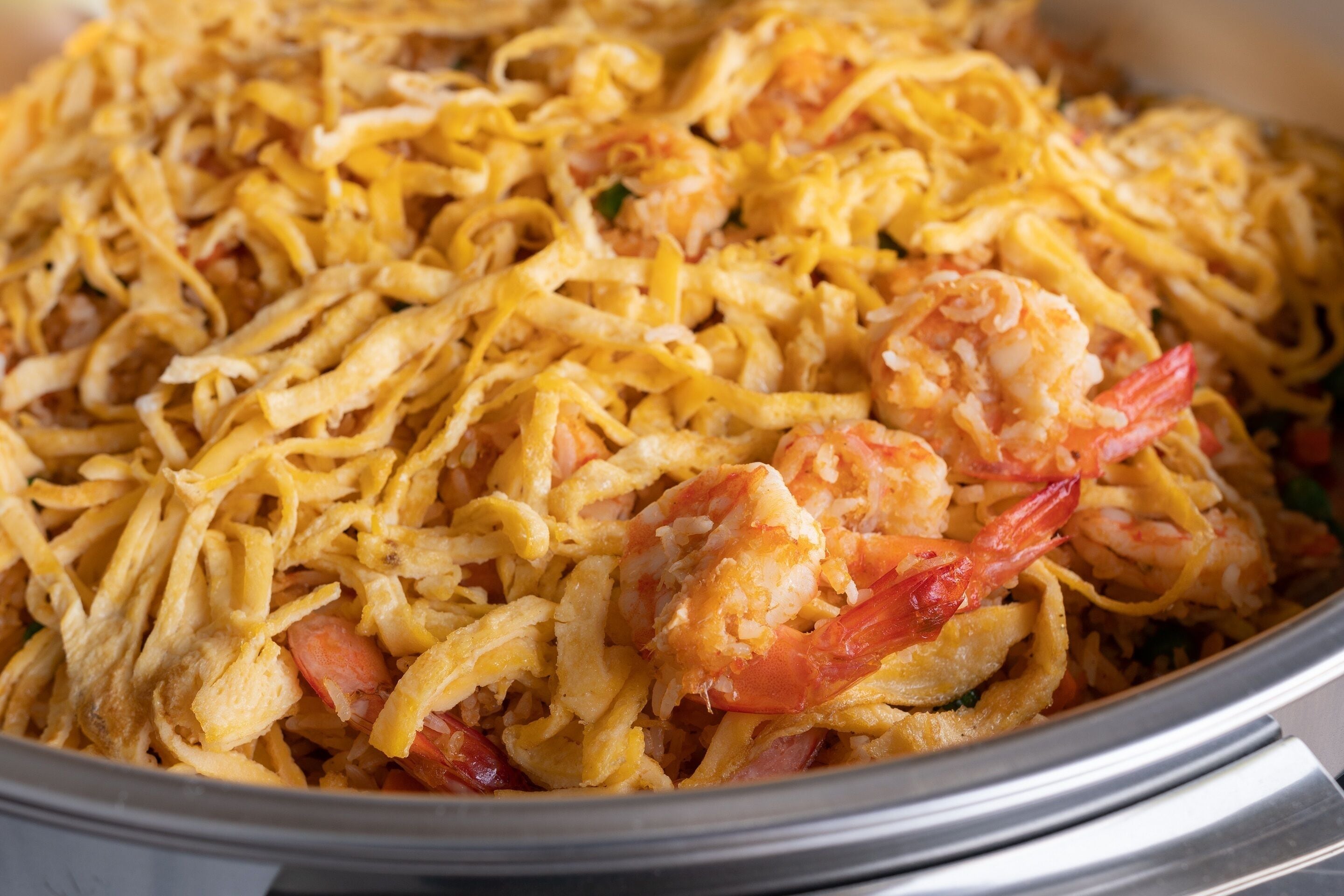 A close-up of a dish with noodles, shrimp, and vegetables.